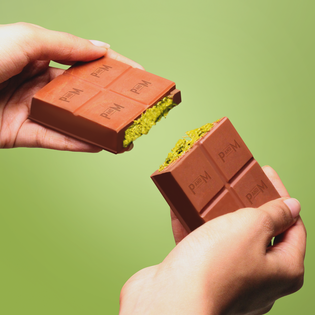 Cross-section of Dubai Chocolate showing vibrant green pistachio and crispy kunafa layers inside milk chocolate shell.